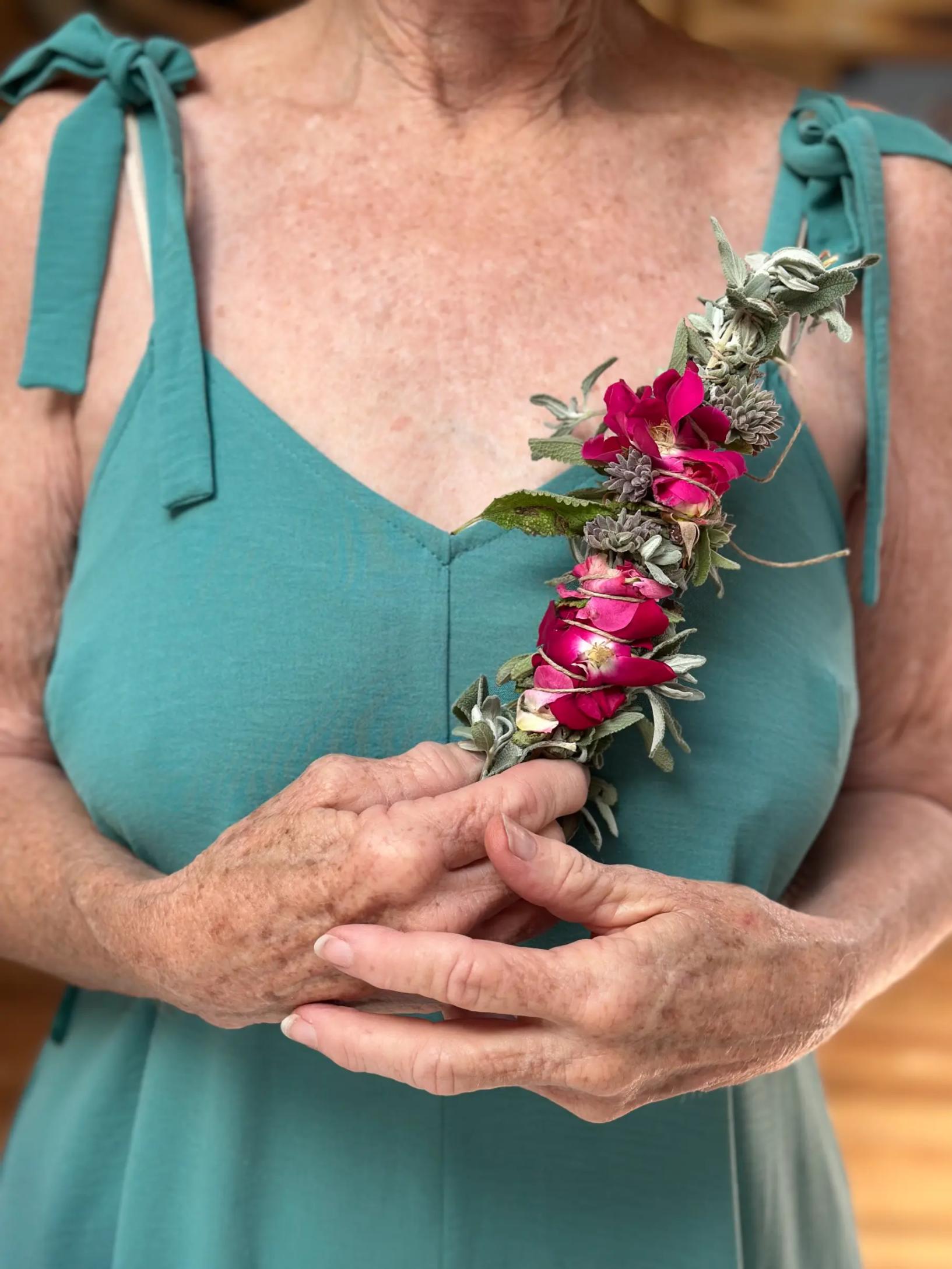 Person in turquoise top holding a pink flower corsage.